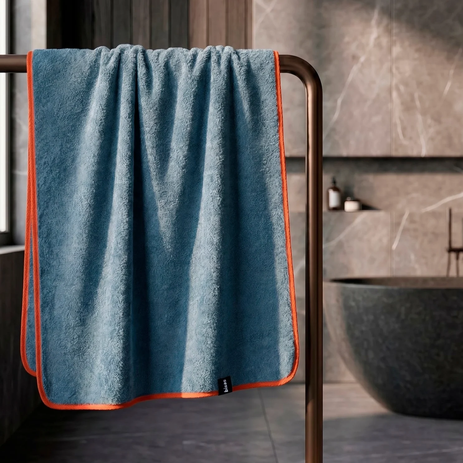 Рушник Bises Nature Bath у відтінку Deep Azure з контрастною помаранчевою окантовкою на тримачі у ванній кімнаті