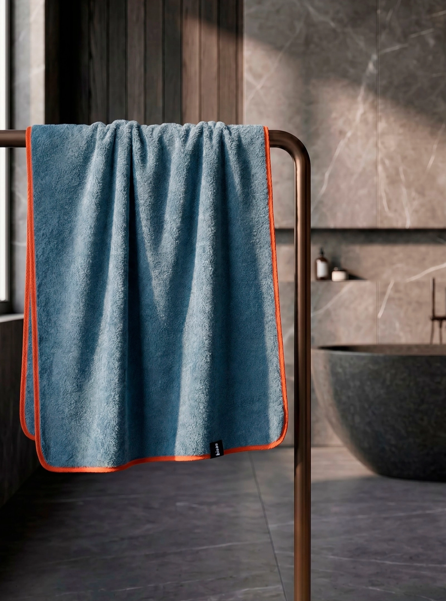 Рушник Bises Nature Bath у відтінку Deep Azure з контрастною помаранчевою окантовкою на тримачі у ванній кімнаті