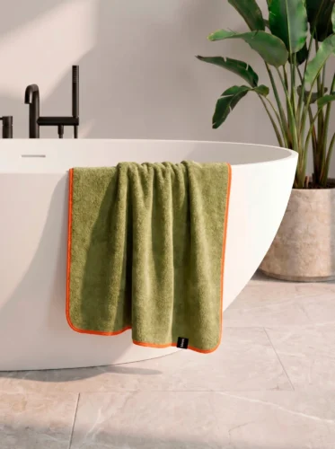 Рушник Bises Nature Bath у відтінку Pistachio Green з контрастною помаранчевою окантовкою на ванні