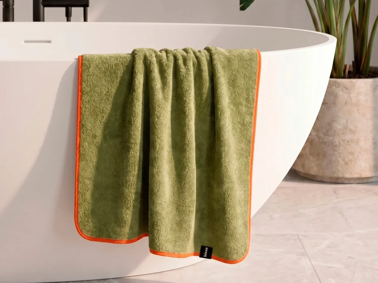 Рушник Bises Nature Bath у відтінку Pistachio Green з контрастною помаранчевою окантовкою на ванні